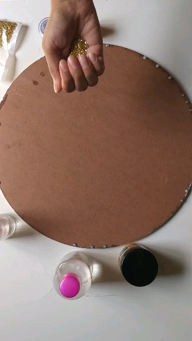 Hand adding gold glitter to a round board during the making process