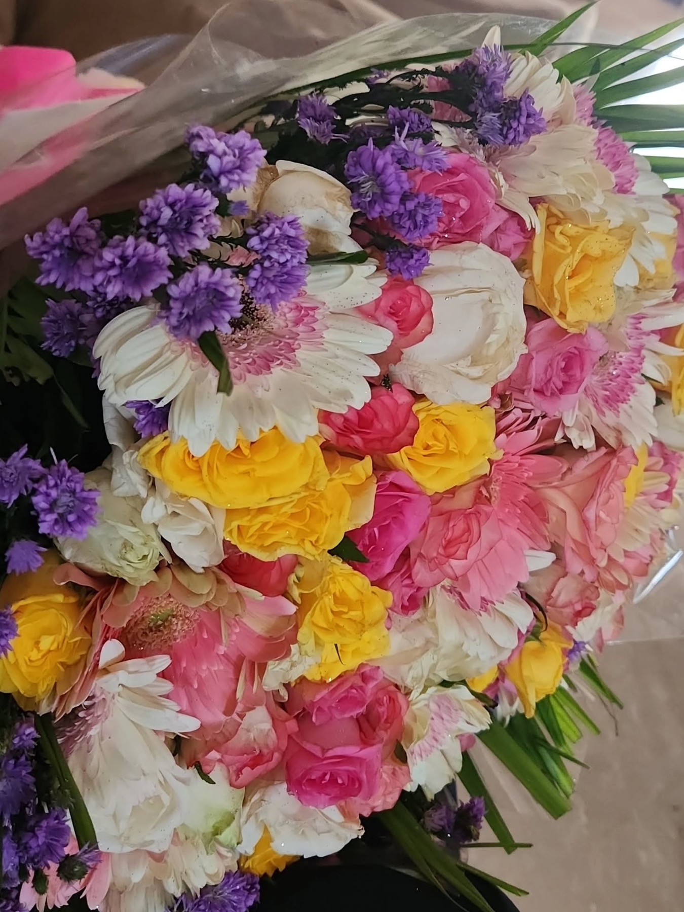 Bright bouquet of purple, pink, yellow, and white flowers arranged by the studio